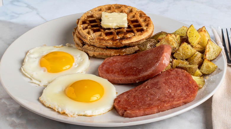 fried eggs with waffles served with spam and home fries