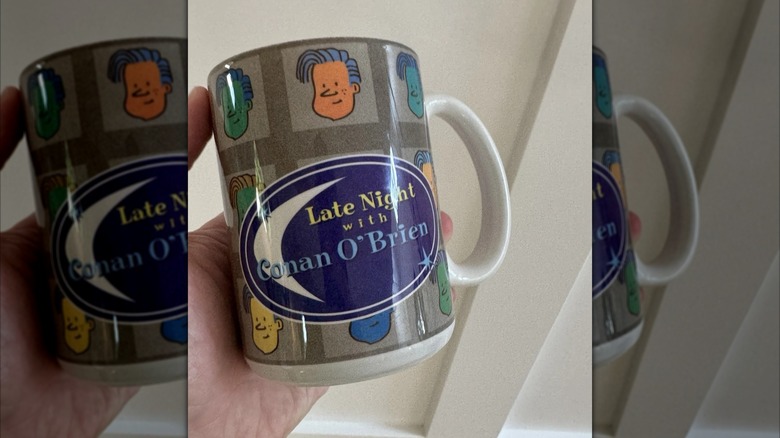Mirrored image of hand holding Late Night With Conan O' Brien mug