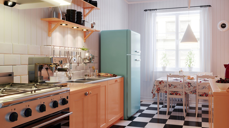 vintage kitchen with blue refrigerator, black and white tile, pastel cabinets, and wooden paneling