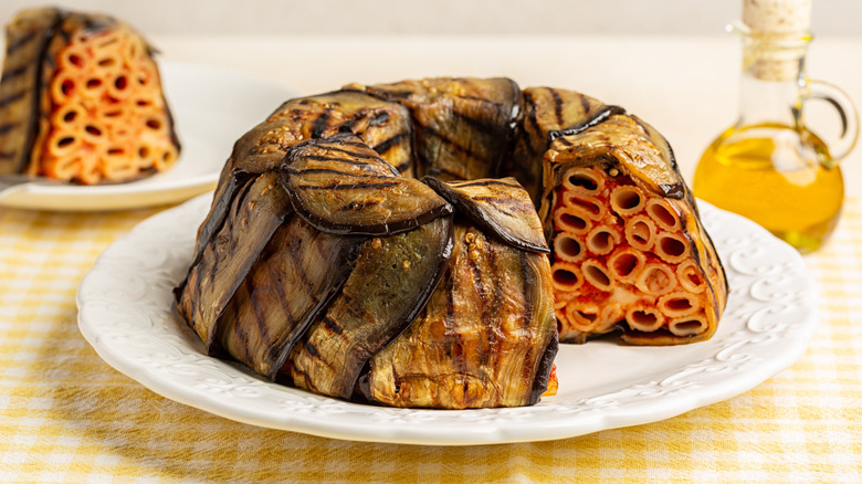 Timballo with a slice out of it on white plate