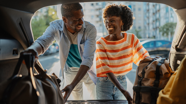 Man and woman smiling at one another as they pack car trunk
