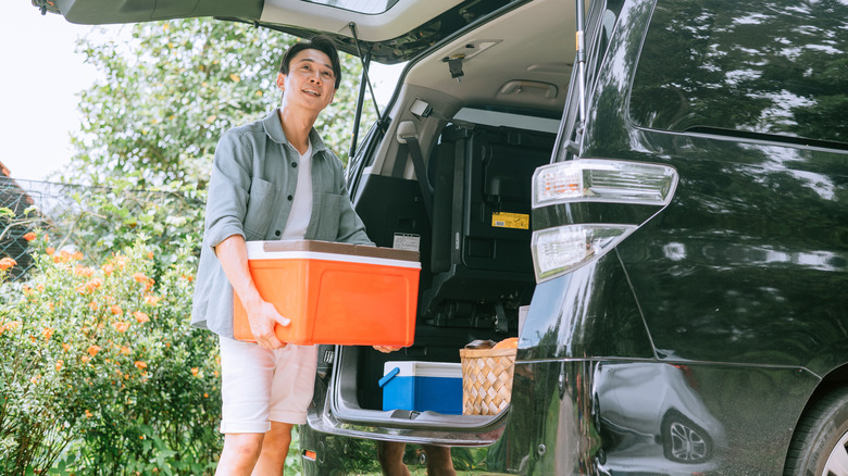 Man loading cooler into back of car