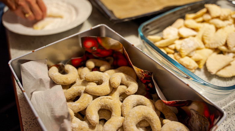 Christmas cookies being placed in tin box and glass container