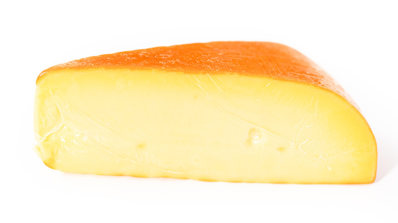 Big slice of smoked gouda on white background