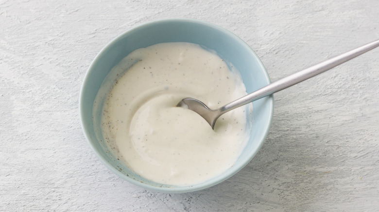 Caesar dressing in blue bowl with spoon