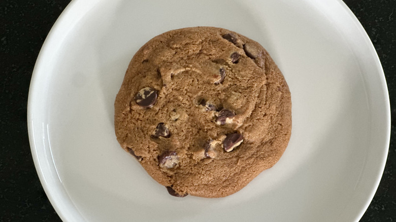 Overhead image of white plate with chocolate chip cookie