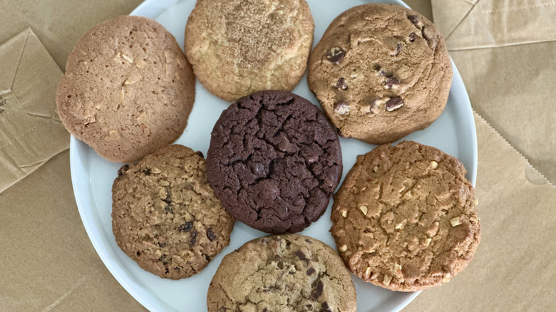 Overhead image of white plate on brown paper bags with seven different cookies
