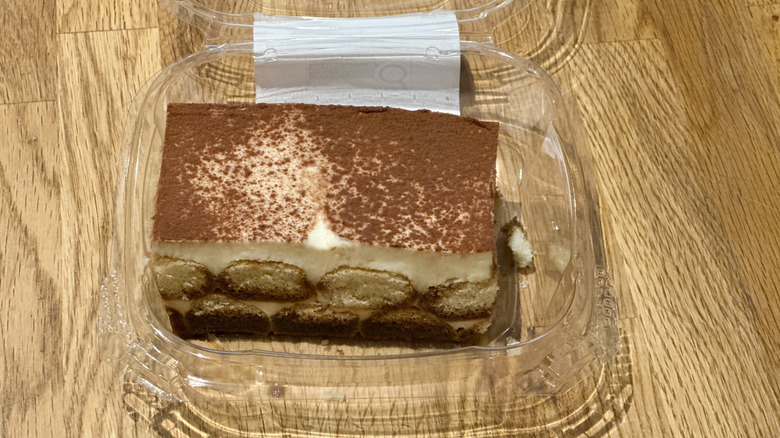 Plastic container of slice of Whole Foods Tiramisu on wooden countertop