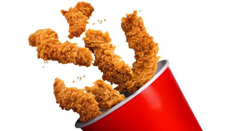 Chicken strips flying into a red bucket