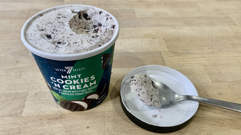 opened Mint Cookies 'N Cream pint with spoonful of ice cream next to it