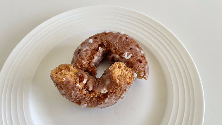 Dunkin' Pumpkin Donut torn in half on a white plate