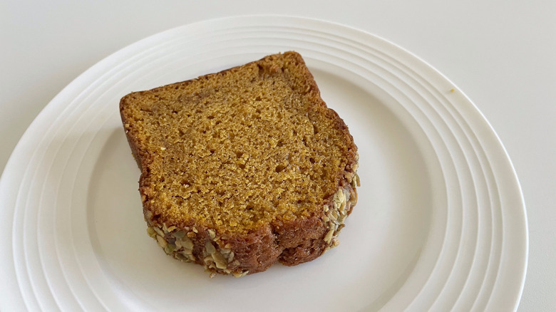 Close up of a slice of Starbucks Pumpkin Pepita Loaf on a white plate