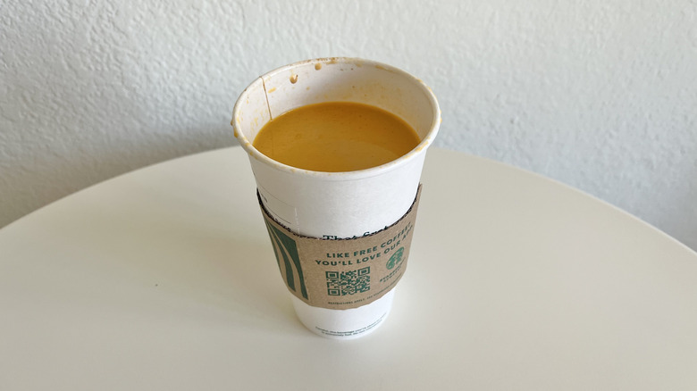 Cup of Starbucks Pumpkin Spice Latte in a paper cup on a white table