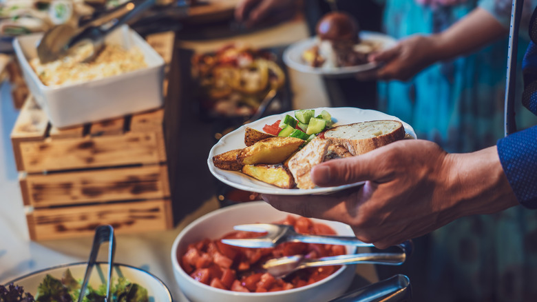 banquet-style meal with bread, potatoes, vegetables on plate being held