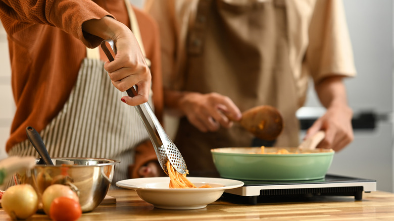 couple cooking spaghetti in a kitchen