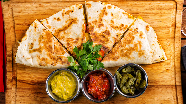 A photo of a quesadilla from above on a board.