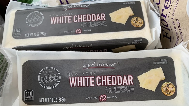 Two packages of Emporium Selection Aged Reserved New York White Cheddar Cheese on a newspaper.
