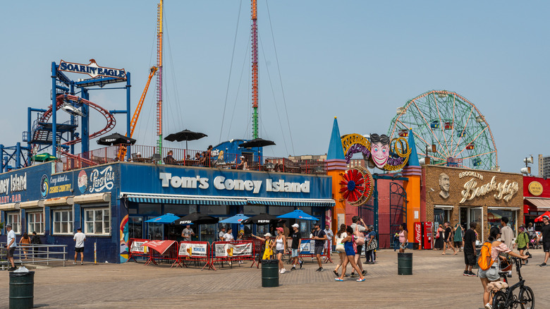 Coney Island boardwalk with storefronts and rides in background
