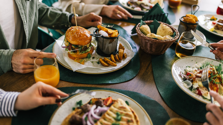 Diners at restaurant eating meals like burgers with fries.