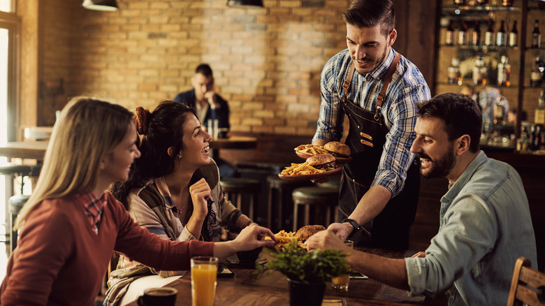 Waiter serving meals to guests at a restaurant.