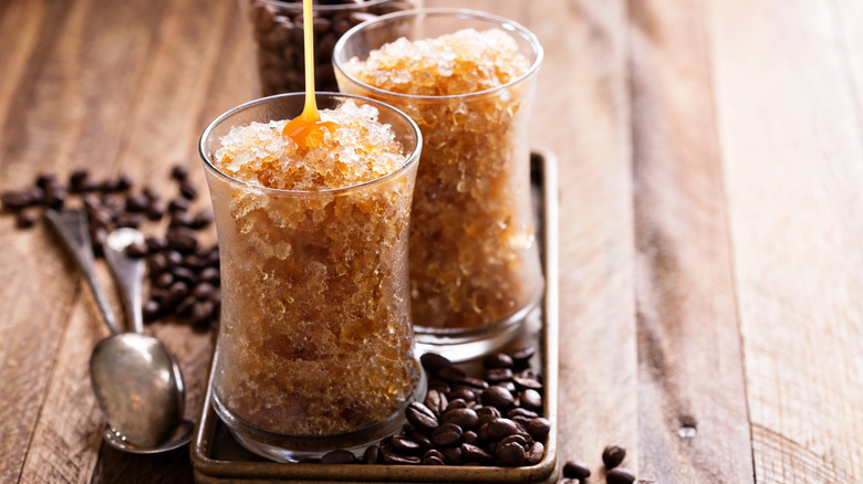 Coffee granita in small glasses with caramel syrup surrounded by coffee beans