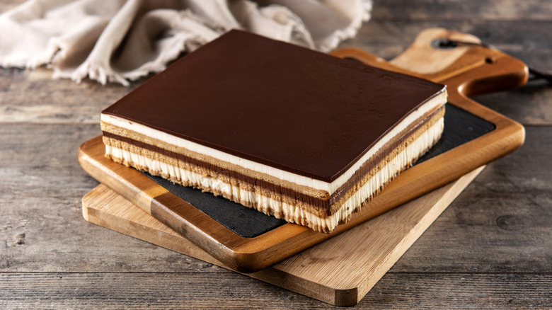 Opera cake dessert slice on wooden board on wooden table