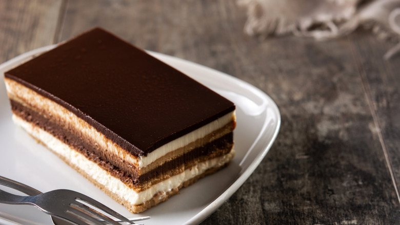 Opera cake on a white plate on a wooden table