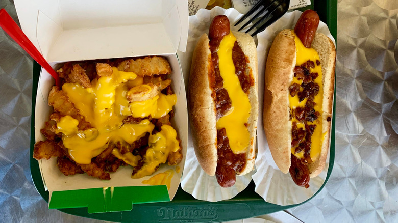 A container of cheese fries sits near two chili cheese dogs