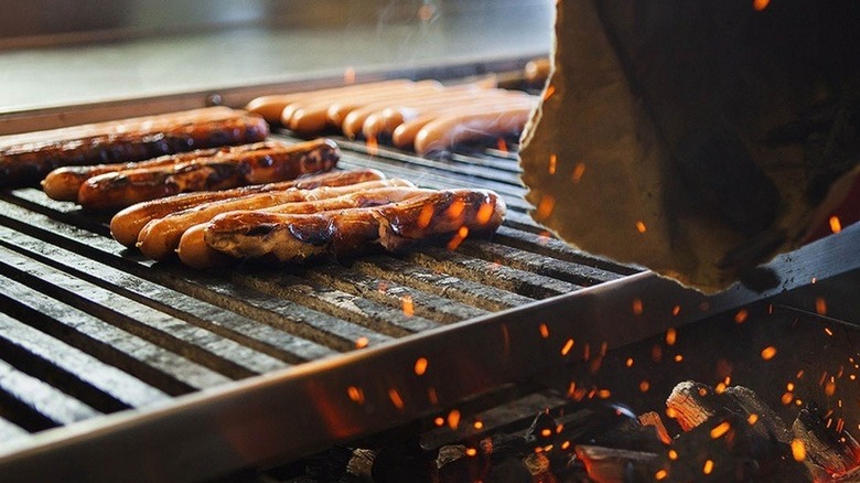 Hot dogs sitting on a grill over charcoal