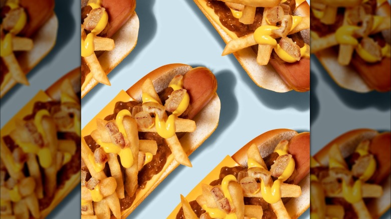 A group of hot dogs covered in mustard, fries, and chili