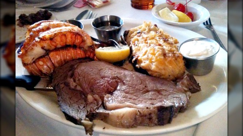 Prime rib on plate with lobster tail and twice baked potato