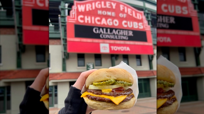 A Billy Goat Tavern cheeseburger being held up in front of the wrigley field marquee