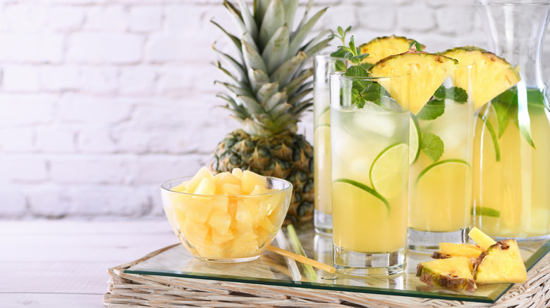 Two pineapple drinks with fresh pineapple and lime