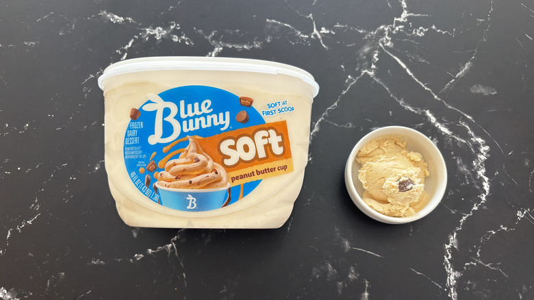 Blue Bunny peanut butter chip ice cream tub next to small bowl of ice cream