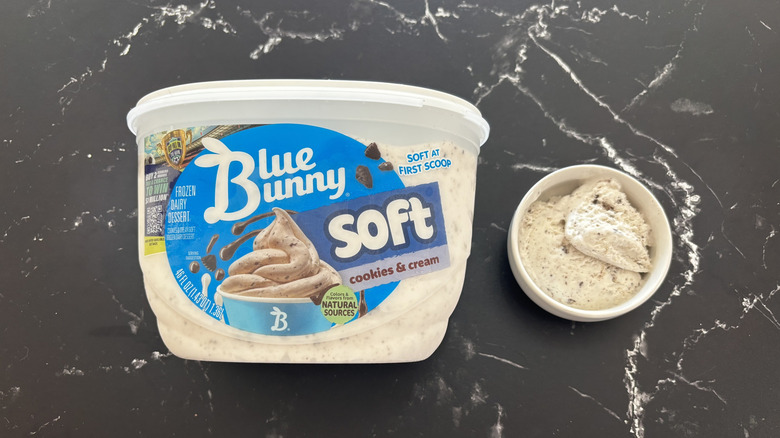 Blue Bunny cookies & cream ice cream tub next to small bowl of ice cream