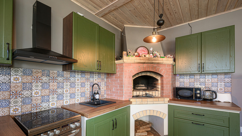 kitchen with olive green cabinets, colorful backsplash tiles, and a brick oven