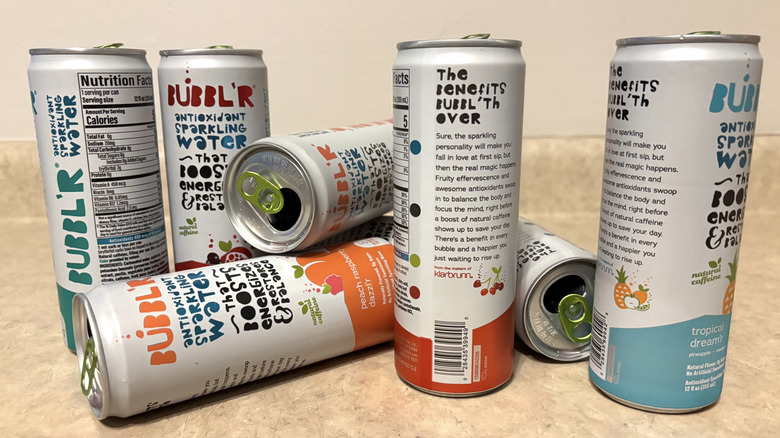 An assortment of Bubbl'r sparkling water cans on a neutral background.