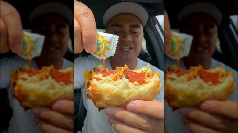 Person drizzling sachet of spicy sauce onto Burger King breakfast sandwich