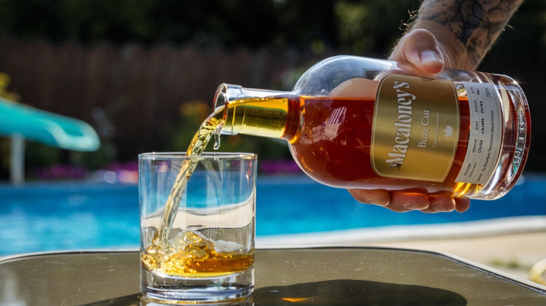 Someone pouring Macaloney's whisky into glass.