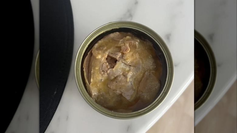 Open can of foie gras on marble counter, mirrored image