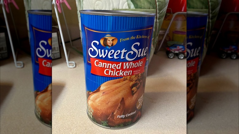 A can of Sweet Sue Canned Whole Chicken Without Giblets on a countertop, mirrored image