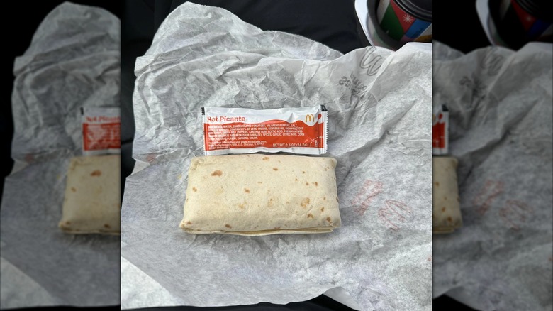 Mirrored image of burrito next to sauce packet on open packaging