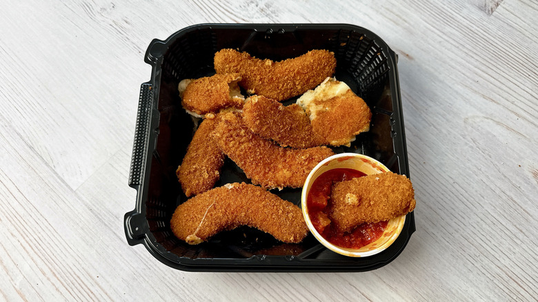 Outback Steakhouse mozzarella boomerangs in a take out container with marinara dipping sauce on the side