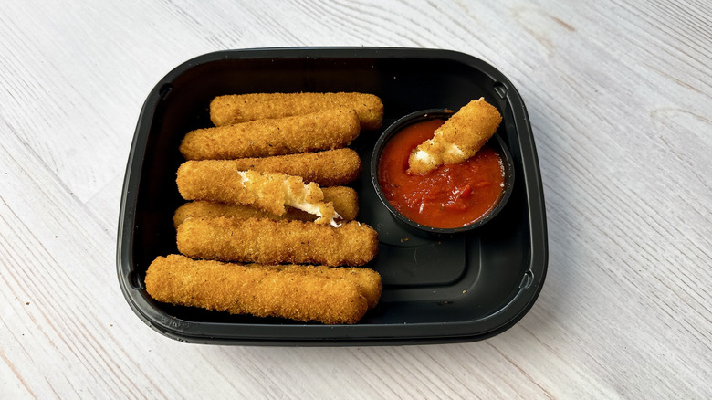 Applebee's mozzarella sticks in a takeout container with marinara dipping sauce on the side