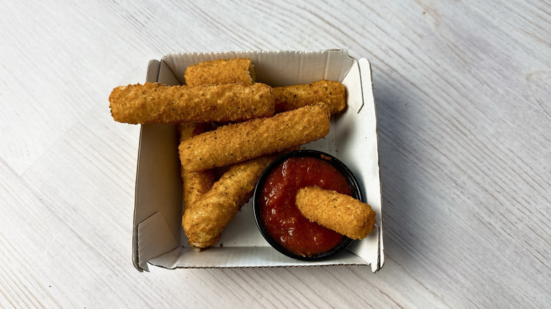 Buffalo Wild Wings mozzarella sticks in a takeout box with marinara dipping sauce