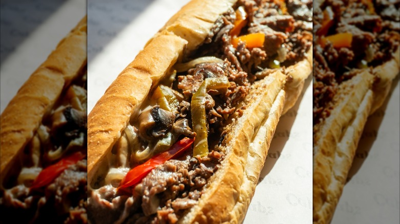 Philly cheesesteak with peppers on paper in bright light