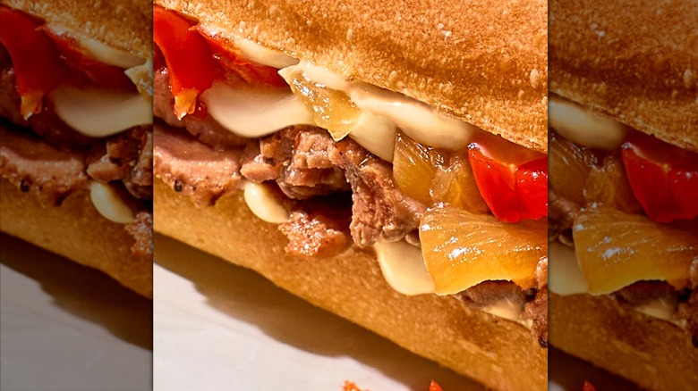 Close-up of cheesesteak with peppers and onions on ciabatta
