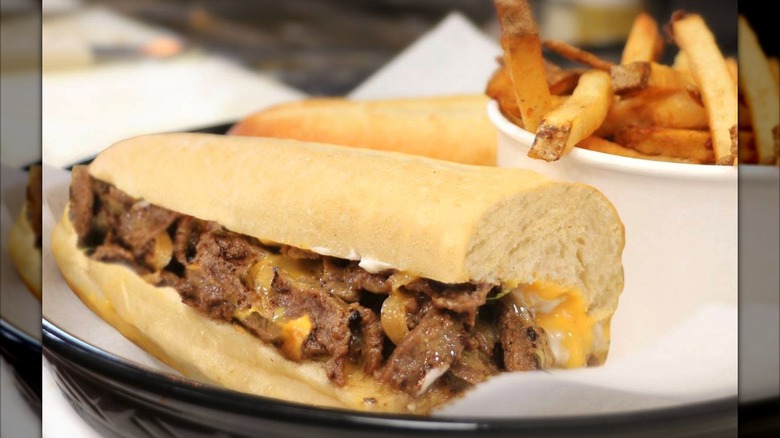 Cheesesteak on plate with fries in background