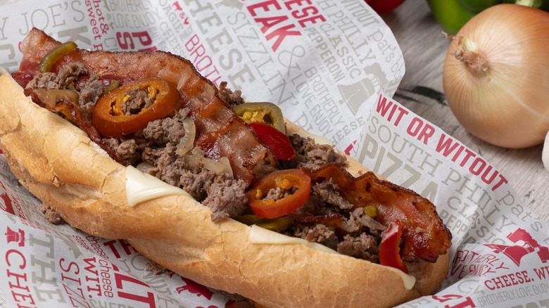 Cheesesteak on paper with peppers and bacon