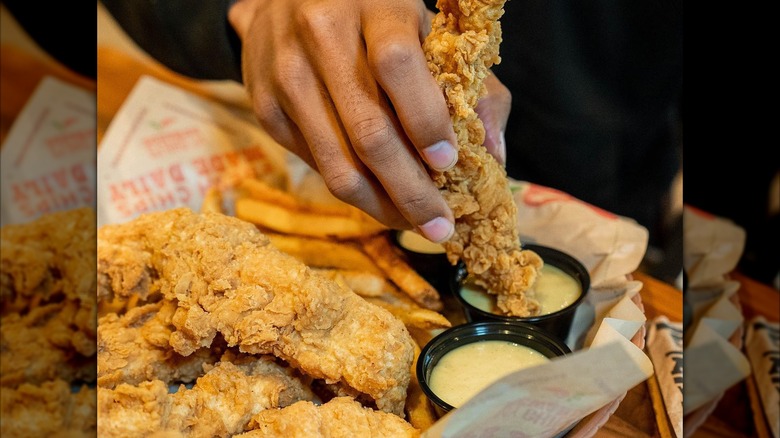 Person dipping chicken tender into sauce at Chili's